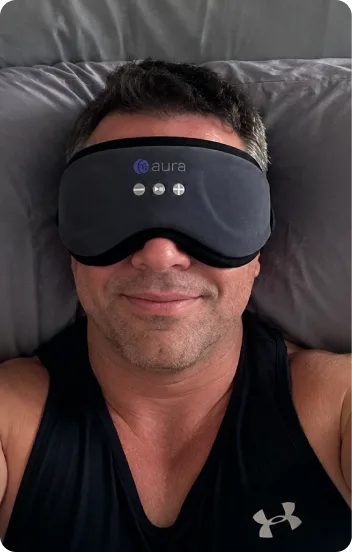 Customer photo of a man lying on his pillow wearing the AURA Bluetooth Sleep Mask